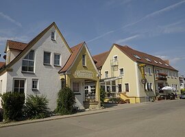 Ein Gebäudekomplex mit zwei großen Häusern des Gasthof und Metzgerei Kleemann. Auf der linken Seite ein weißes dreistöckiges Haus mit der Aufschrift Gästehaus Kleemann. daneben ein Vordach aus Glas. Daran schließt sich ein langes dreistöckiges Haus mit gelber Fassade an.